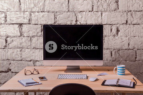 Desk With Various Gadgets And Office Supplies. Computer, Smart Phone And Stationery Around The Workplace. White Brick Wall.