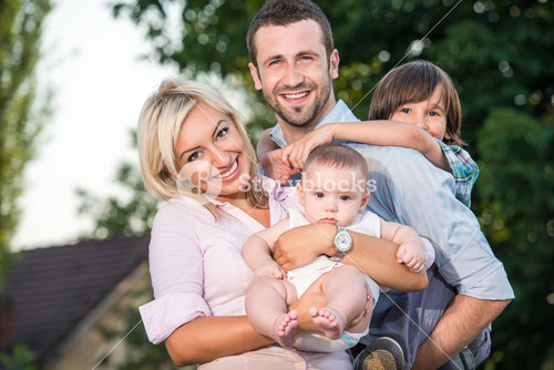Happy Family Posing Outdoors In Front Of House