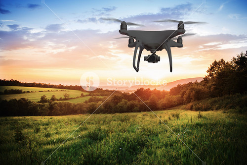 Silhouette Of Hovering Drone Taking Pictures Of Green Meadows And Hills At Sunset