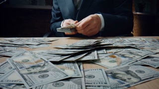 Unknown Rich Man Counting Heap Us Dollars Sitting Office Desk In Elegant Suit Close Up. Businessman Hands Putting Hundred Banknotes American Currency On Pile At Table. Manager Calculating Money Cash.
